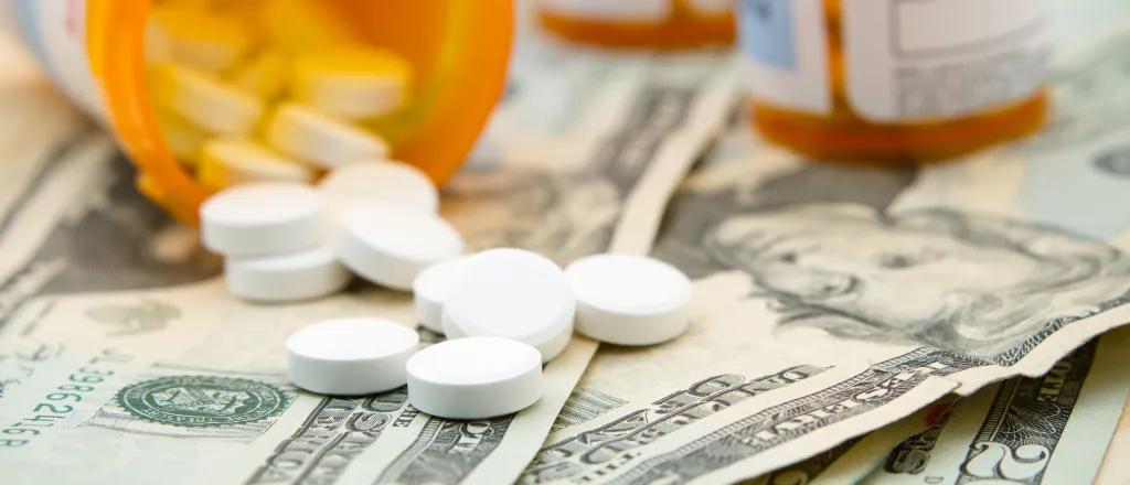 PROMO HIRES Health - Medicine Drugs Pills Money Perscription Bottle - iStock - RonOrmanJr Bottle of prescription drugs spilling its contents on paper money