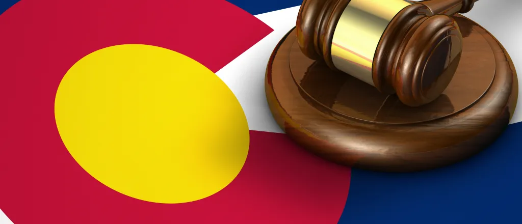 PROMO HIRES Legal - Court Law Colorado Flag Gavel Justice - iStock - NiroDesign Gavel resting on a strike plate on top of a Colorado state flag.