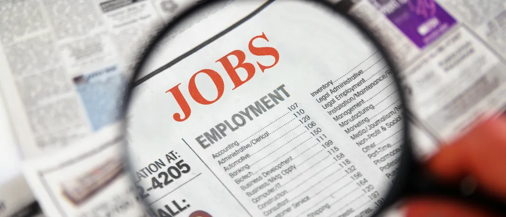 PROMO HIRES Miscellaneous - Classified Ad Help Wanted Jobs Newpaper - iStock - zimmytws Magnifying glass over a newspaper showing the Jobs section