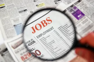 PROMO HIRES Miscellaneous - Classified Ad Help Wanted Jobs Newpaper - iStock - zimmytws Magnifying glass over a newspaper showing the Jobs section